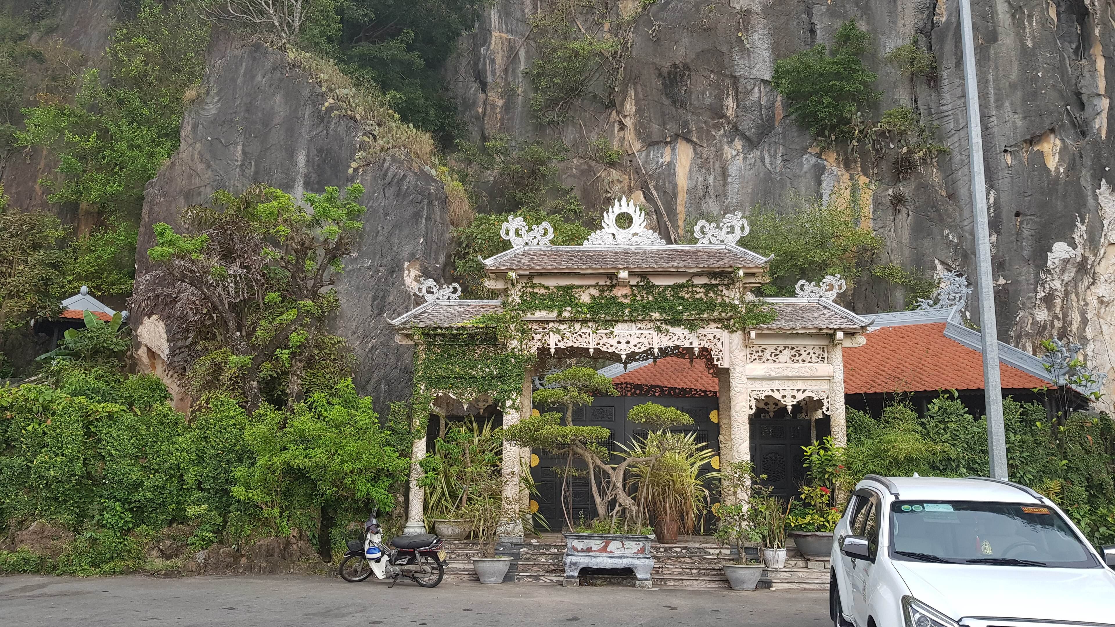 An ornate stone gateway at the foot of the Marble Mountains, with the cliff behind